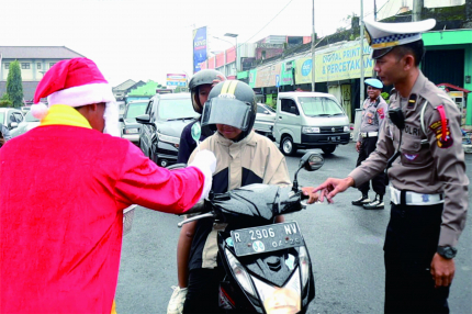 Wayang Bawor menyampaikan imbauan tertib lalu lintas, sedangkan Sinterklas membagikan hadiah berupa permen dan cokelat untuk pengendara yang melintas di depan Pos Pengamanan Terpadu Operasi Lilin Candi 2022 yang berada di Alun-alun Purbalingga, Minggu 25 Desember 2022.