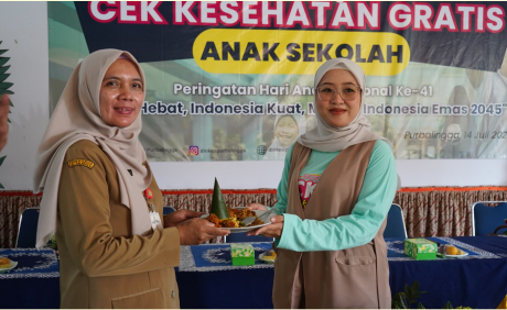 Bunda PUSPA II Kabupaten Purbalingga, Denita Dimas Prasetyahani memberikan potongan gunungan nasi tumpeng kepada Kepala SMP Negeri 1 Purbalingga, Eni Rundiati usai peluncuran perdana CKG, di SMP Negeri 1 Purbalingga, Senin 14 Juli 2025.