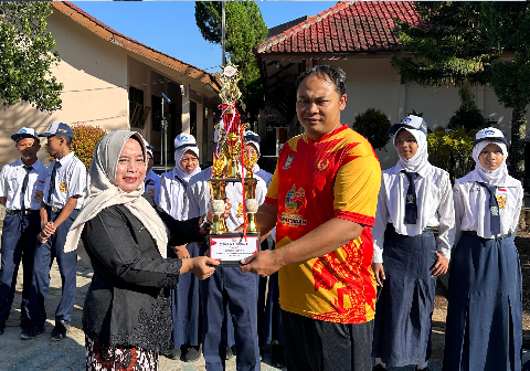 Guru PJOK SMP Negeri 1 Kalimanah, Dedi Irwanto menerima piala kejuaraan dari Plt Kepala SMP Negeri 1 Kalimanah, Tjandra Irawati usai upacara bendera di sekolahan itu, Senin 18 Mei 2026
